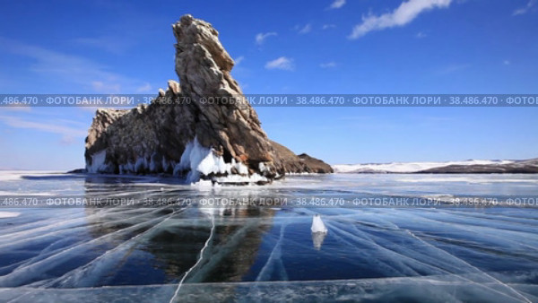 Frozen Baikal |Lake on clear winter cold day. Beautiful blue ice with cracks near rocky tip of Ogoy Island at Cape Dragon. Winter ice travel. Стоковое видео, видеограф Виктория Катьянова / Фотобанк Лори
