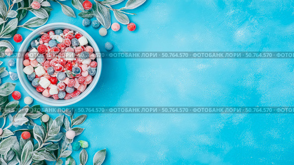 Frozen Berry Mixture with Frosted Leaves on a Blue Surface: Festive Winter Treat. Стоковое AI-изображение, AI-художник Данила Большаков / Фотобанк Лори