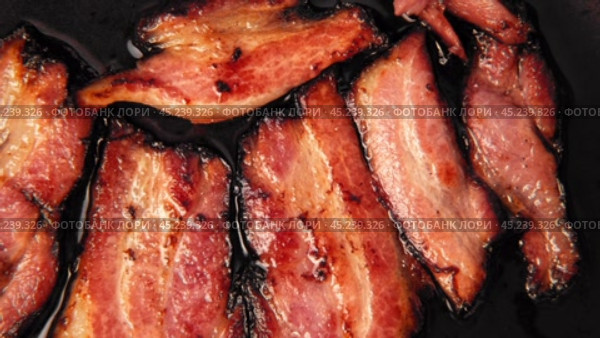 Frying Bacon Slices in a Pan. Crispy Pieces of Delicious Red Thin Smokey Bacon Fried in a Hot Skillet. Traditional Breakfast. Smoked Bacon Rasher or Strip Being Cooked. Grill. Fat High Calorie Food. Стоковое видео, видеограф Марина Демидюк / Фотобанк Лори