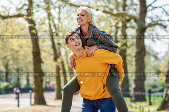 Funny couple in a urban park. Boyfriend carrying his girlfriend on piggyback. Love and tenderness, dating, romance. Lifestyle concept. Funny couple in a urban park. Boyfriend carrying his girlfriend on piggyback. Стоковое фото, агентство Ingram Publishing / Фотобанк Лори