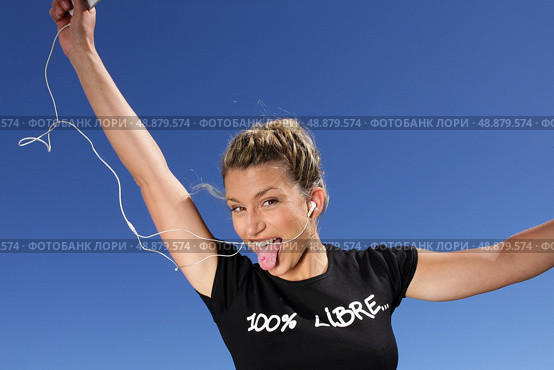 Funny woman listening to music outdoors through digital player. Стоковое фото, агентство Ingram Publishing / Фотобанк Лори