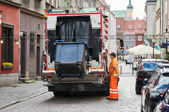 garbage and waste removal services. Worker loading waste bin into truck at city. Стоковое фото, фотограф Дмитрий Калиновский / Фотобанк Лори