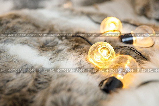Garland lamps lie on fluffy, cozy fur blanket. Стоковое фото, фотограф Aleksandra Selivanova / Фотобанк Лори