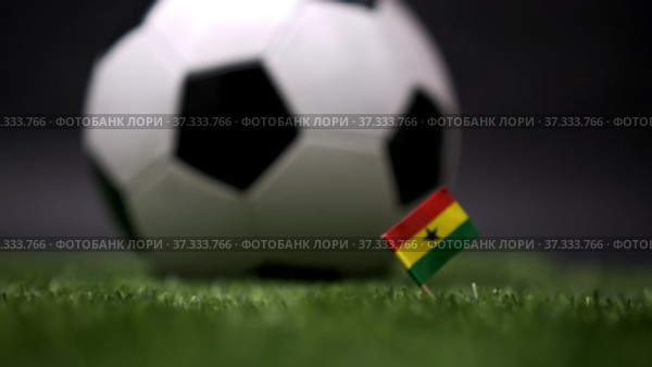 Ghana flag on the football field. Soccer championship. Football classic black and white ball rolls in the background. Sports Competition. The national flag of the country. Green fresh lawn grass. Стоковое видео, видеограф Ирина Ткачук / Фотобанк Лори