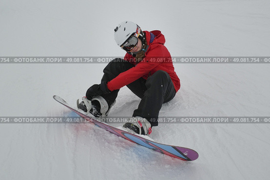 Girl adjusting snowboard, Whistler Blackcomb, Vancouver, British Columbia, Canada. Стоковое фото, агентство Ingram Publishing / Фотобанк Лори