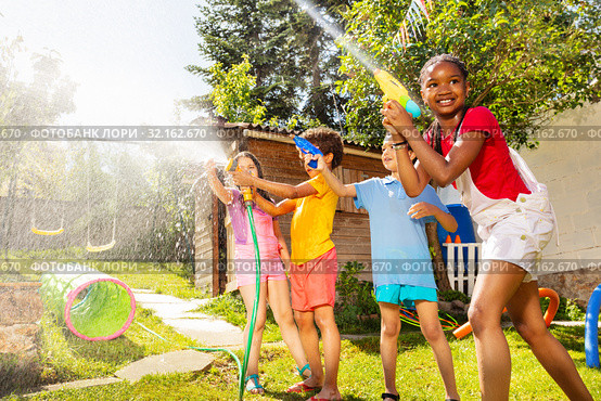 Girl and friends shoot water pistols on summer day. Стоковое фото, фотограф Сергей Новиков / Фотобанк Лори