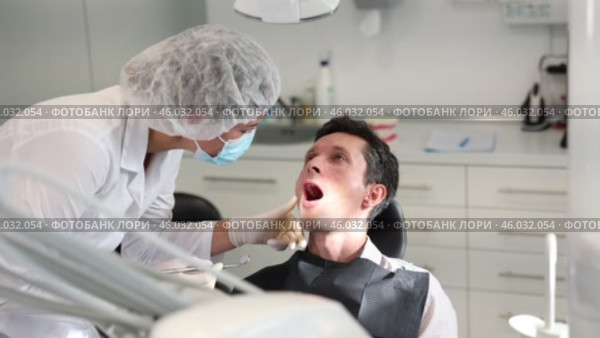 Girl doctor dentist in white coat examines oral cavity of male patient in dentistry. Стоковое видео, видеограф Яков Филимонов / Фотобанк Лори