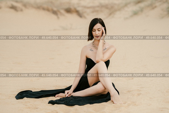 girl in a black long dress in a sandy desert under a blue sky. Стоковое фото, агентство Ingram Publishing / Фотобанк Лори