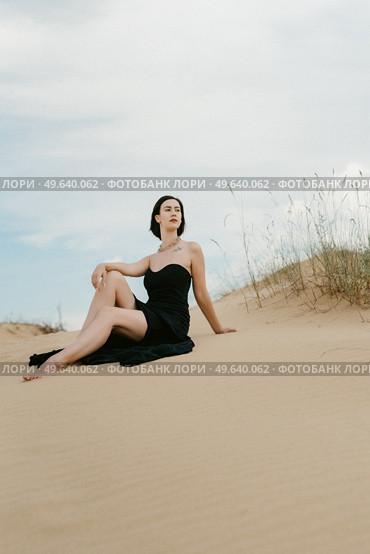 girl in a black long dress in a sandy desert under a blue sky. Стоковое фото, агентство Ingram Publishing / Фотобанк Лори