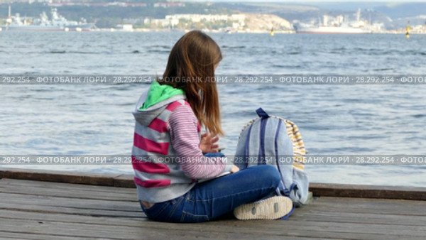 Girl is reading a book on the embankment near the sea. Стоковое видео, видеограф Tatiana Kravchenko / Фотобанк Лори