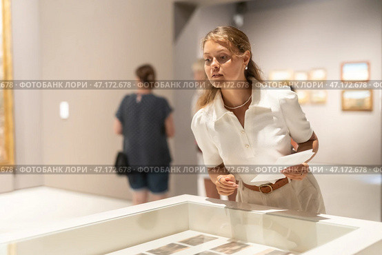 Girl looks at various paintings and drawings at an art exhibition in museum. Стоковое фото, фотограф Яков Филимонов / Фотобанк Лори