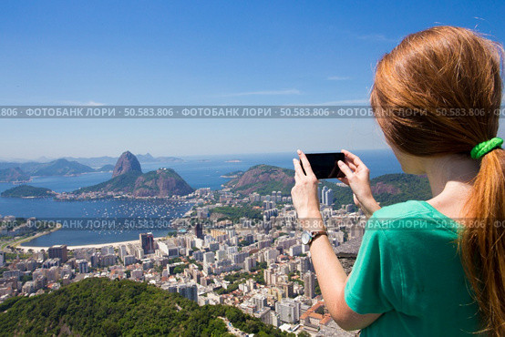 girl tourist  takes a picture of  Rio landscape and Pao de Asucar with smartphone. Стоковое фото, агентство Ingram Publishing / Фотобанк Лори