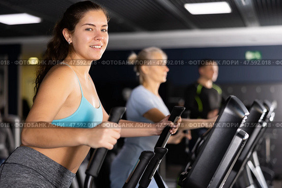 Girl warming up on elliptical machine before training in gym. Стоковое фото, фотограф Яков Филимонов / Фотобанк Лори