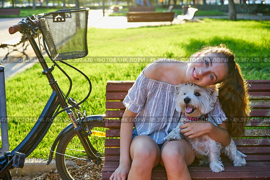 Girl with dog sitting in a park bench with turf grass background outdoor. Стоковое фото, агентство Ingram Publishing / Фотобанк Лори
