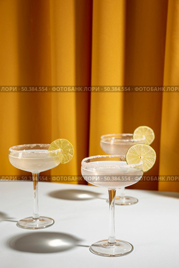 glass margarita cocktail garnish with lime table against yellow curtain. Стоковое фото, агентство Ingram Publishing / Фотобанк Лори