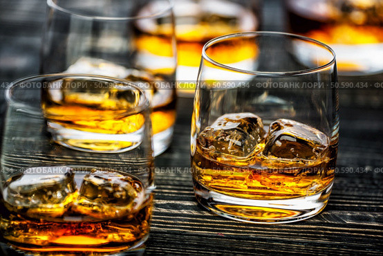 Glass of scotch whiskey and ice on a black wooden background,selective focus. Стоковое фото, агентство Ingram Publishing / Фотобанк Лори
