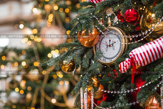 Golden retro clock on a decorated Christmas tree 2026. A beautiful background for New Year's Eve or Christmas. The clock hands on the dial show 12 o'clock. Стоковое фото, фотограф Photojuli / Фотобанк Лори