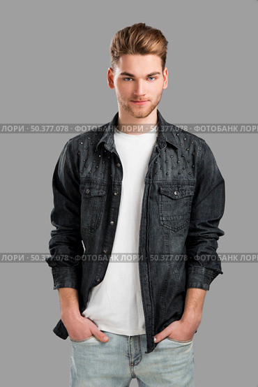 Good looking young man smiling with hands in the pockets, isolated over a gray background. Стоковое фото, агентство Ingram Publishing / Фотобанк Лори