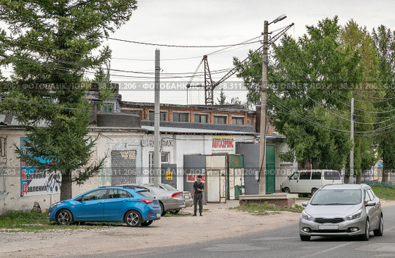Город Алексин Тульской области. Автосервис и шиномонтаж на улице Матросова, 3. По дороге едет машина (2022 год). Редакционное фото, фотограф Наталья Николаева / Фотобанк Лори