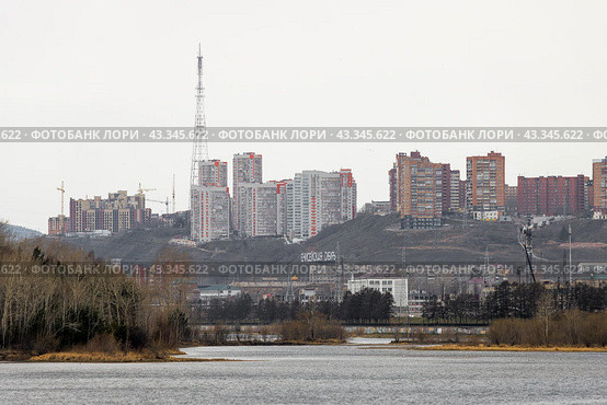 Город Красноярск, Красноярский край, Россия. Вид на многоэтажные жилые дома и телебашню на высоком холмистом берегу реки Енисей. На склоне надпись «Енисейская Сибирь». Большой сибирский город. (2023 год). Редакционное фото, фотограф Андрей Степанов / Фотобанк Лори