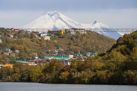 Город Петропавловск-Камчатский, Камчатский край, Россия. Красивый осенний городской пейзаж. Вид на здания на склоне холма. Вдалеке вулкан Авачинская Сопка. На переднем плане озеро Култучное. Путешествие на Камчатку. Дальний Восток России. Стоковое фото, фотограф Андрей Степанов / Фотобанк Лори