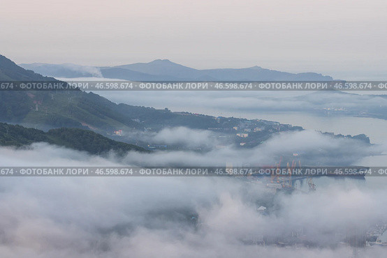 Город Петропавловск-Камчатский, Камчатский край, Дальний Восток России. Вид сверху на портовый город на берегу залива. Красивый утренний пейзаж на рассвете. Туман над городом. Авачинская бухта, Тихий океан. Стоковое фото, фотограф Андрей Степанов / Фотобанк Лори
