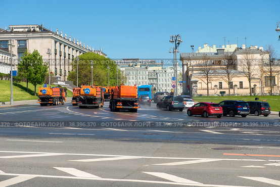 Городские дорожные службы дезинфицируют улицы в центре Москвы во время эпидемии коронавируса COVID-19 в России. Поливальные машины моют асфальт городской дороги, Москва, Россия (2021 год). Редакционное фото, фотограф Pukhov K / Фотобанк Лори