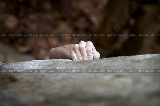 Grabing onto a small handhold, a climber makes his way to the top. His hand is covered in chalk, and there is a very shallow depth of field. The white specks are small pieces of chalk dust flying through the air. Стоковое фото, агентство Ingram Publishing / Фотобанк Лори