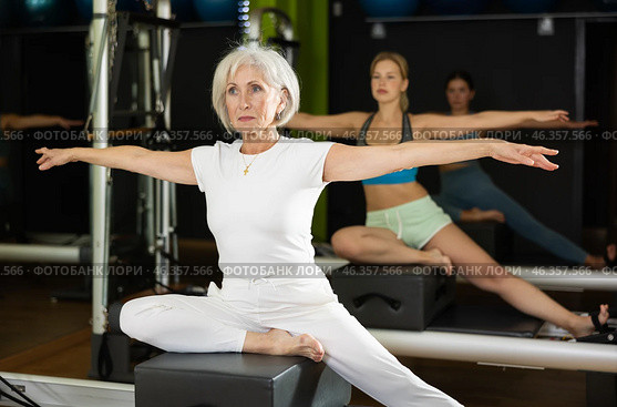 Gray-haired woman sitting on a Pilates platform. Стоковое фото, фотограф Яков Филимонов / Фотобанк Лори