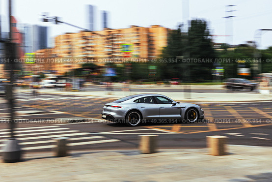Grey Porsche Taycan Turbo S sports sedan on a city street in motion.  Racing along the highway, side view. Редакционное фото, фотограф Андрей Иванов / Фотобанк Лори