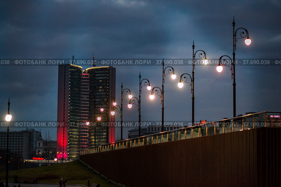 Grey soviet constructivist building with evening illumination and street lightings on grey cloudy sky at sunset or dusk. Moscow (2014 год). Редакционное фото, фотограф Alexey Rezvykh / Фотобанк Лори