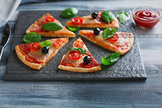 Грифельная тарелка с кусочками вкусной пиццы на деревянном столе. Стоковое фото, фотограф Pixel_shot / Фотобанк Лори