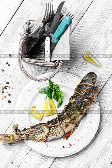 grill fish on light plate. whole carcass of fish grilled on light plate on light background. Стоковое фото, агентство Ingram Publishing / Фотобанк Лори