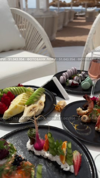 Grilled salmon steak with crispy skin sauteed vegetables and lemon served in outdoor restaurant in summer light A wooden table with a variety of dishes containing seafood, vegetables and fruit.Hand holding a spoon ready to eat pineapple fried rice with shrimp, served in a pineapple bowl, surrounded by fresh fruits and tea on a cozy table setting.Party Sea Food platter with salmon and prawns, low angle view, close-up Sea food party platter, extreme Whole poached salmon with cucumber slices for scales, high end party platter, overhead view Tiger prawns on the grill Macarooni cookies floating on blue background, levitation, macarooni cookies, dessert, sweets, colorful, delicious Two Glasses of Pink Champagne with Macarons and Oranges Elegant seaside celebration with seafood, pink floral decor, and sparkling wine overlooking the ocean. Стоковое видео, видеограф Zita Khasanova / Фотобанк Лори