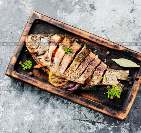 Grilled whole fish with citrus,vegetable and spices on rustic kitchen board.Cooked baked grilled fish. Carp stuffed with vegetables. Стоковое фото, агентство Ingram Publishing / Фотобанк Лори