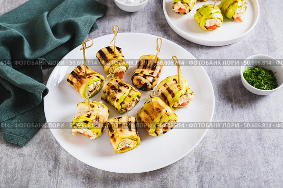 Grilled zucchini rolls filled with cream cheese and tomatoes on a plate on the table. Стоковое фото, фотограф Елена Руй / Фотобанк Лори