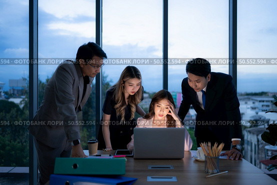 Group of broker international stock traders working actively at night in office, A young woman is working hustle to present a client with friends helping her with information. Стоковое фото, агентство Ingram Publishing / Фотобанк Лори
