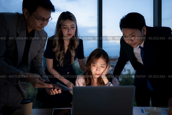 Group of broker international stock traders working actively at night in office, A young woman is working hustle to present a client with friends helping her with information. Стоковое фото, агентство Ingram Publishing / Фотобанк Лори