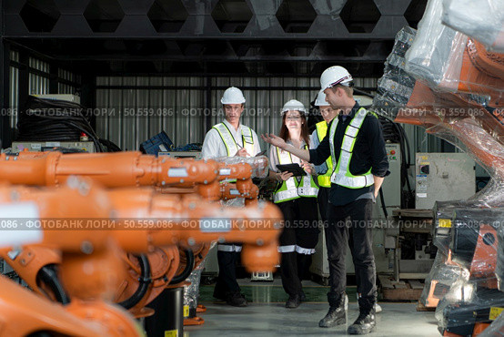 Group of engineers and technicians working together in a robotic arm factory. Inspecting robot arm before delivering to customers. Стоковое фото, агентство Ingram Publishing / Фотобанк Лори