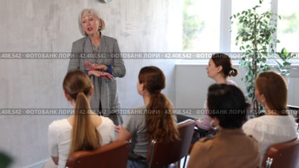 Group of friendly women of different ages sitting around table and communicating in Spanish-speaking club with elderly female tutor. Стоковое видео, видеограф Яков Филимонов / Фотобанк Лори