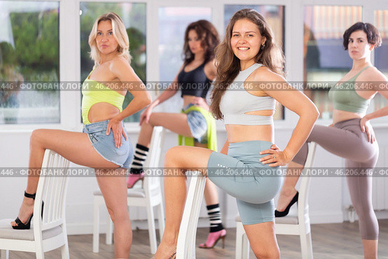 Group of girls unleash their energy and dance passionately near a chair in high heels in a dance studio. His powerful moves combined with elegance of high heels. Стоковое фото, фотограф Яков Филимонов / Фотобанк Лори