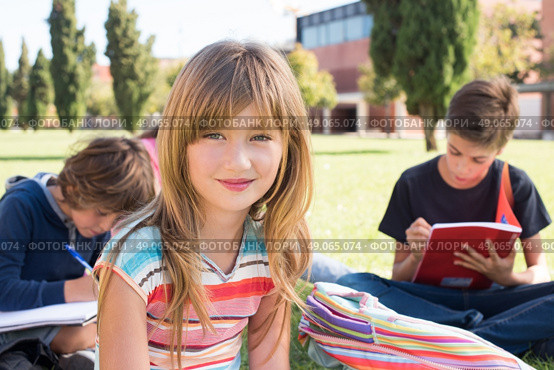 Group of little students sitting on the grass at school. Стоковое фото, агентство Ingram Publishing / Фотобанк Лори