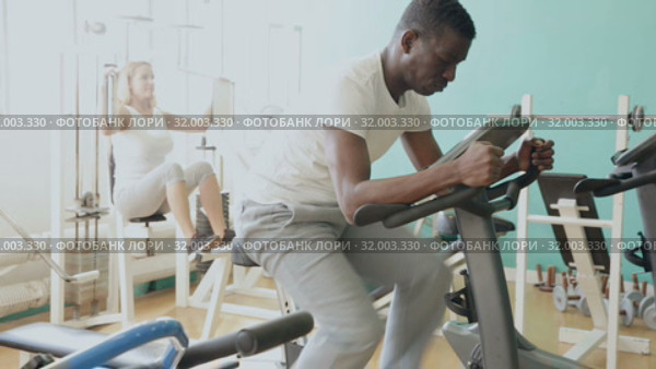 Group of people exercising with weight and on simulators in gym. Стоковое видео, видеограф Яков Филимонов / Фотобанк Лори
