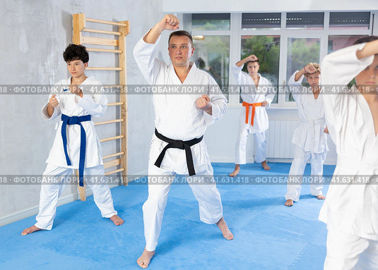 Group of teenagers in kimonos following karate sensei through kata exercises. Стоковое фото, фотограф Яков Филимонов / Фотобанк Лори