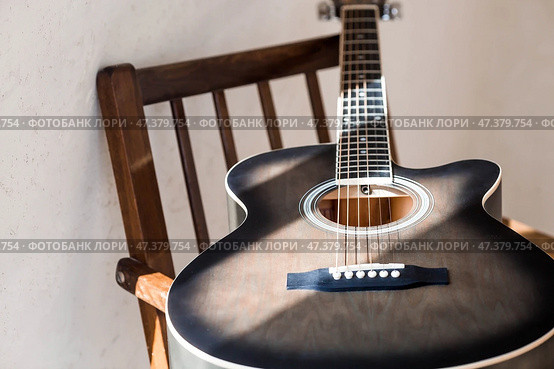 Guitar. Guitar chords. Acoustic guitar. Music. Musical background. An image of an acoustic guitar in a room with a retro armchair. Hard light. Shadows. Стоковое фото, фотограф Photojuli / Фотобанк Лори