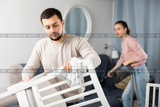 Guy rubbing wooden furniture while wife vacuuming sofa. Стоковое фото, фотограф Яков Филимонов / Фотобанк Лори