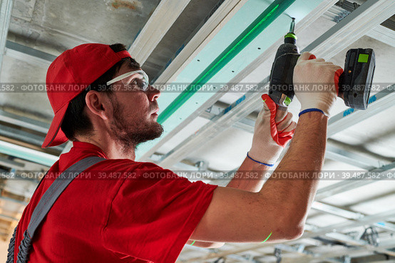 Gypsum plasterboard work. Drywall construction at home. Contractor worker installing metal frame on ceiling. Стоковое фото, фотограф Дмитрий Калиновский / Фотобанк Лори