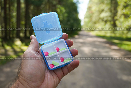 Hand holding daily pill organizer with medical pills in nature. Стоковое фото, фотограф Дмитрий Цветков / Фотобанк Лори