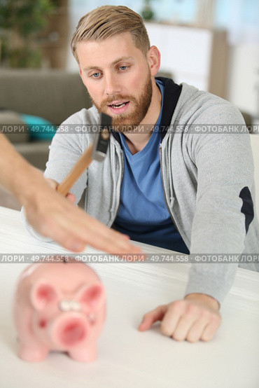 hand preventing man from smashing piggy bank with a hammer. Стоковое фото, агентство Ingram Publishing / Фотобанк Лори