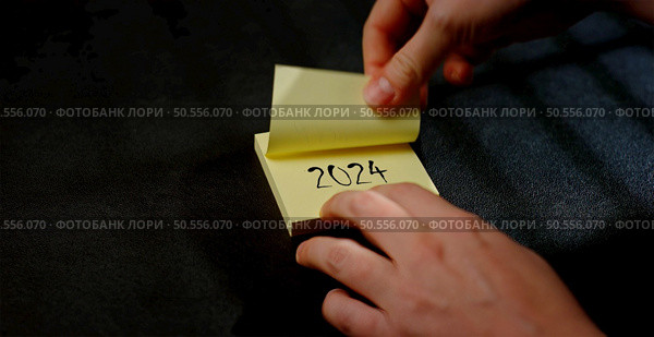 hand pulls off a sticy notes for 2024. Стоковое фото, агентство Ingram Publishing / Фотобанк Лори